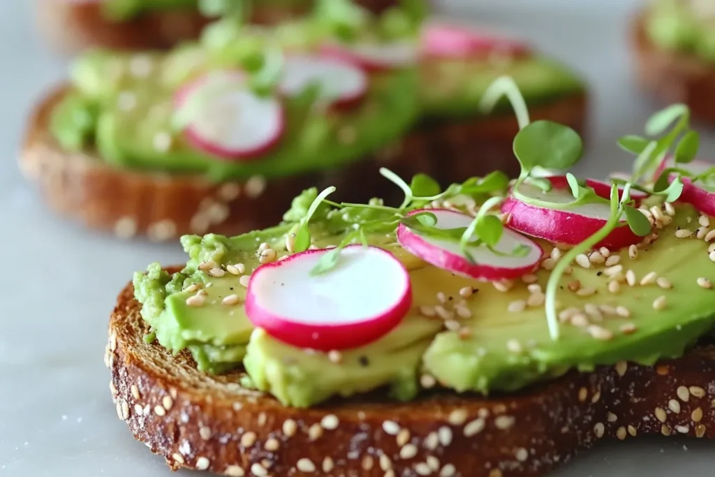 Avocado toast topped with sliced radishes, microgreens, and sesame seeds.